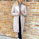 woman wearing quilted taupe long jacket. brand Steve Madden with a drawstring to cinch at waist for more fitted apperance