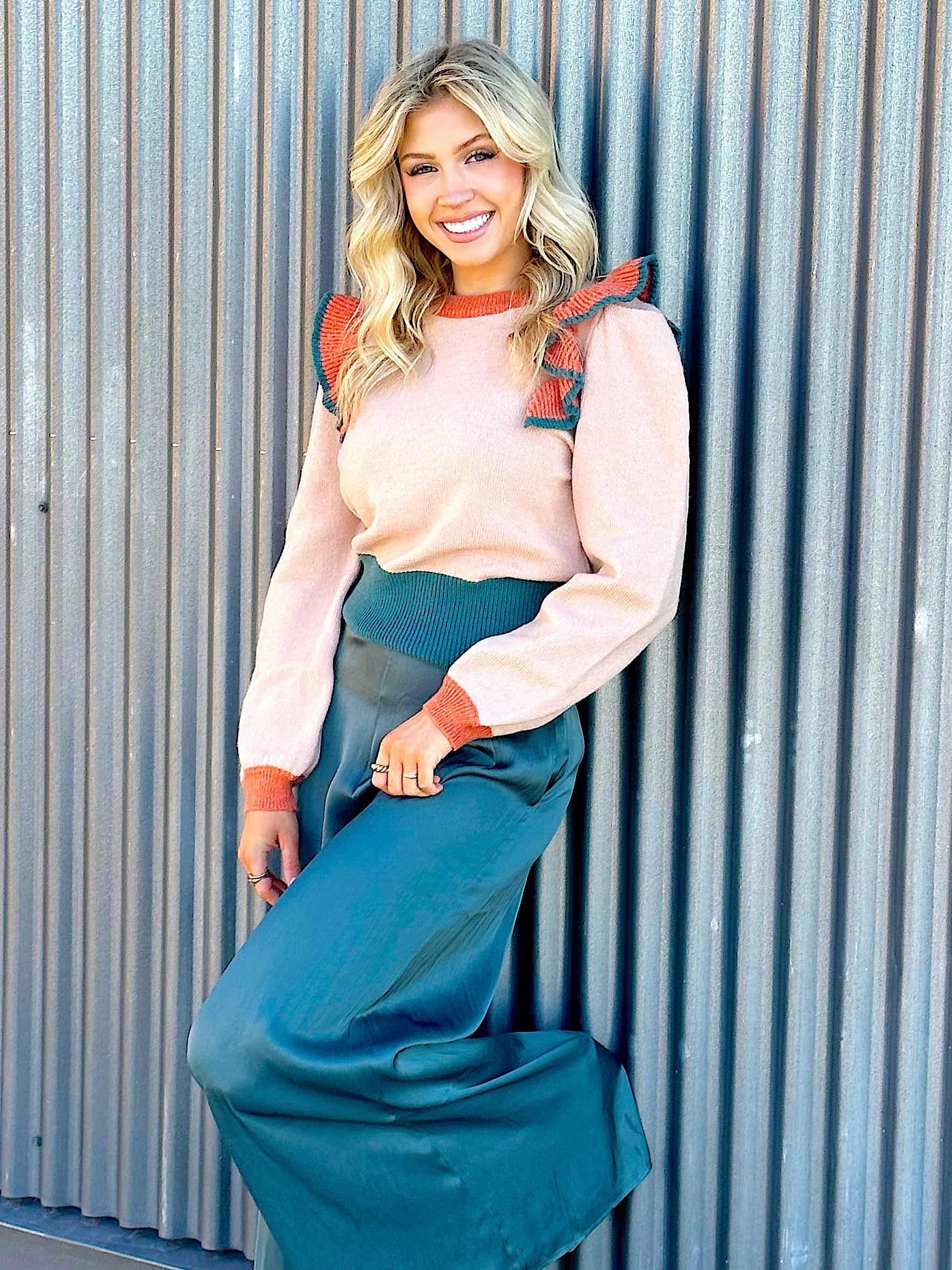 taupe sweater with a slight peach undertone with ruffled and puff sleeves on shoulders. Sweater is color block with orange and emerald green