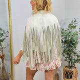 Woman wearing white faux leather fringe jacket with floral hem detail, viewed from behind, styled with white cowboy boots.