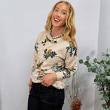 Cream floral print pullover sweater styled with dark jeans and pearl necklace, worn by smiling blonde woman.