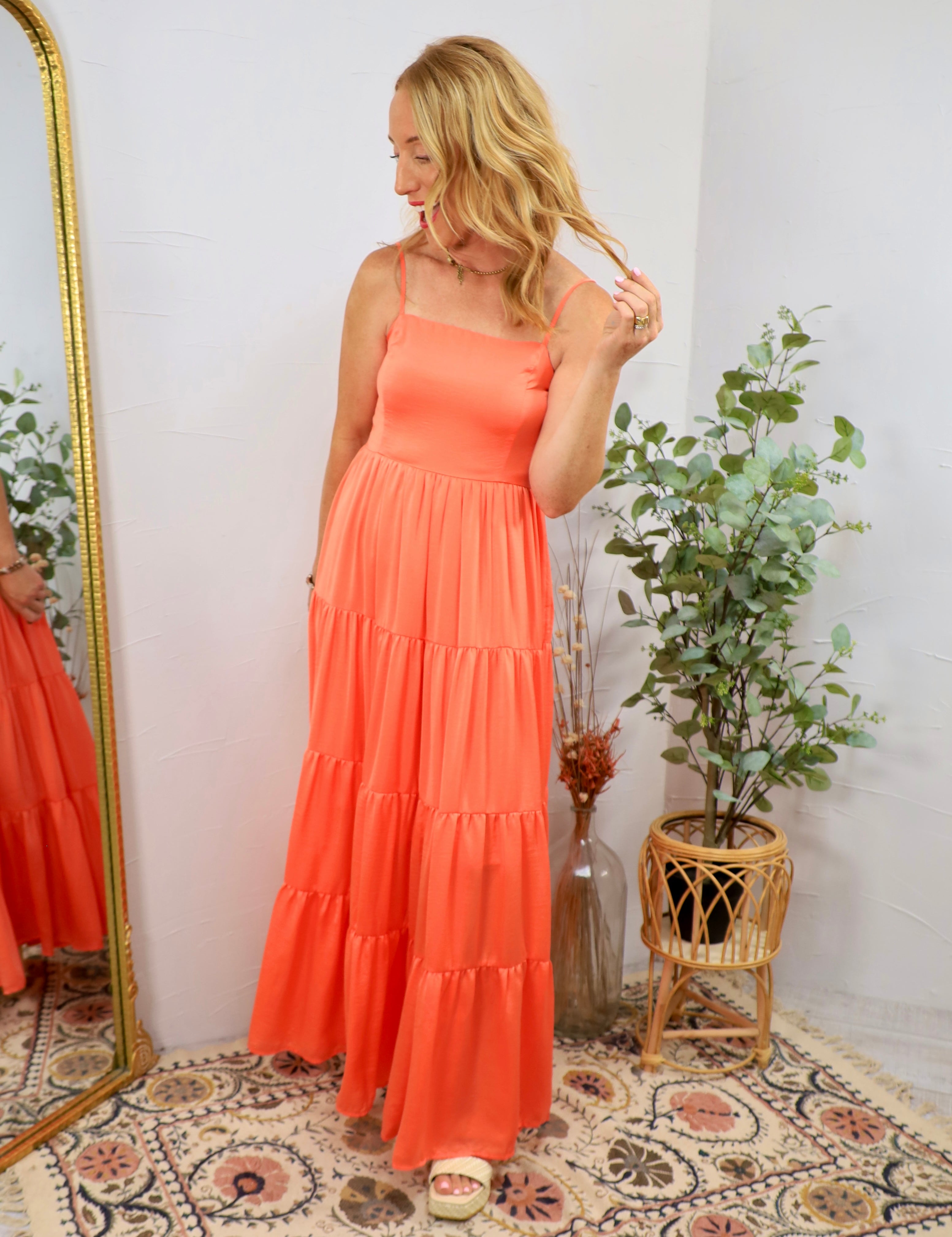 Woman wearing a vibrant coral tiered maxi dress with spaghetti straps and white platform sandals