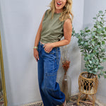 Mid-rise wide-leg cargo denim jeans in medium blue wash, styled with olive sleeveless top and sneakers.