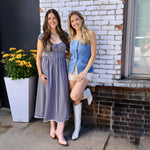 Light blue denim button-front vest styled with printed shorts and white cowboy boots on blonde model.