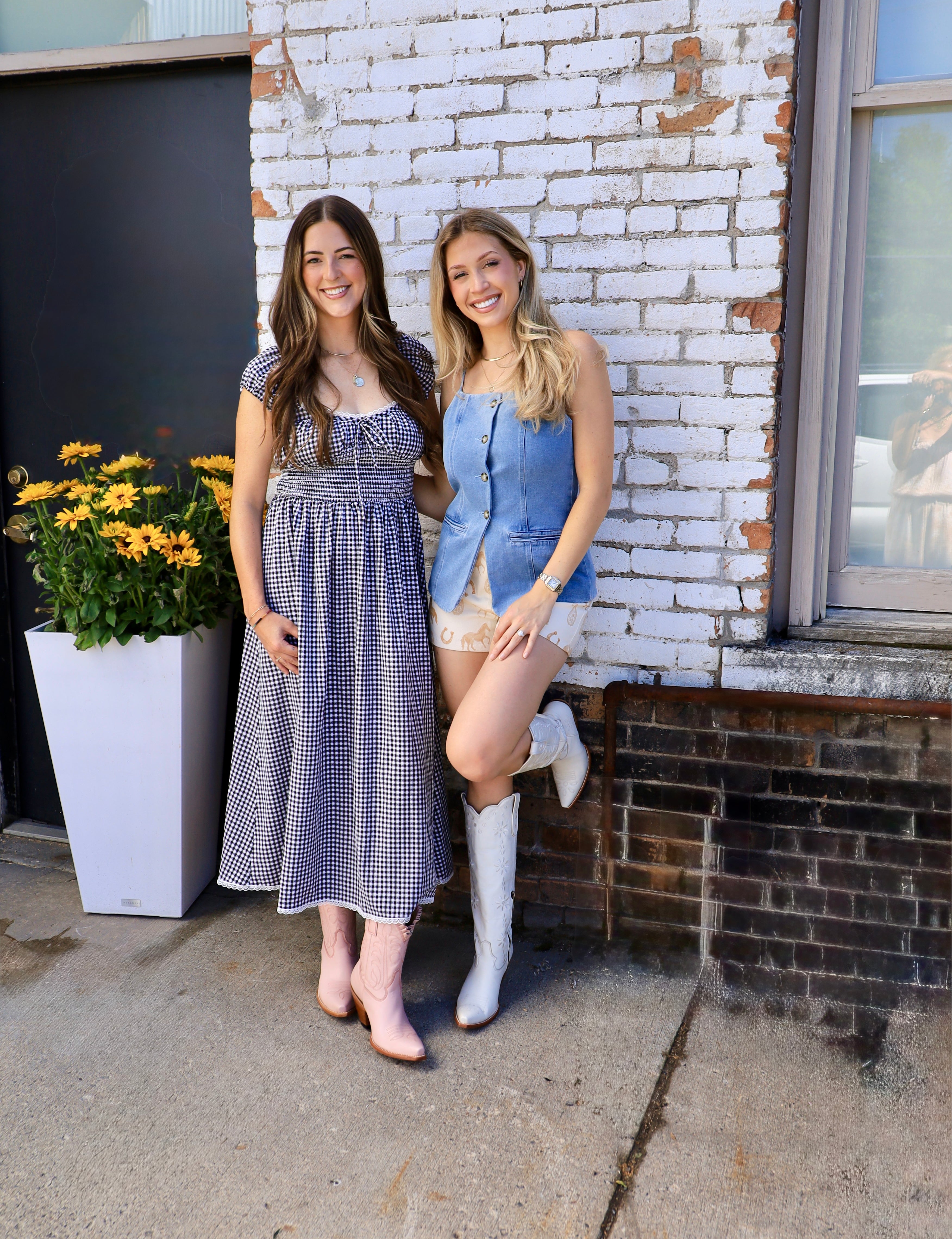 Light blue denim button-front vest styled with printed shorts and white cowboy boots on blonde model.