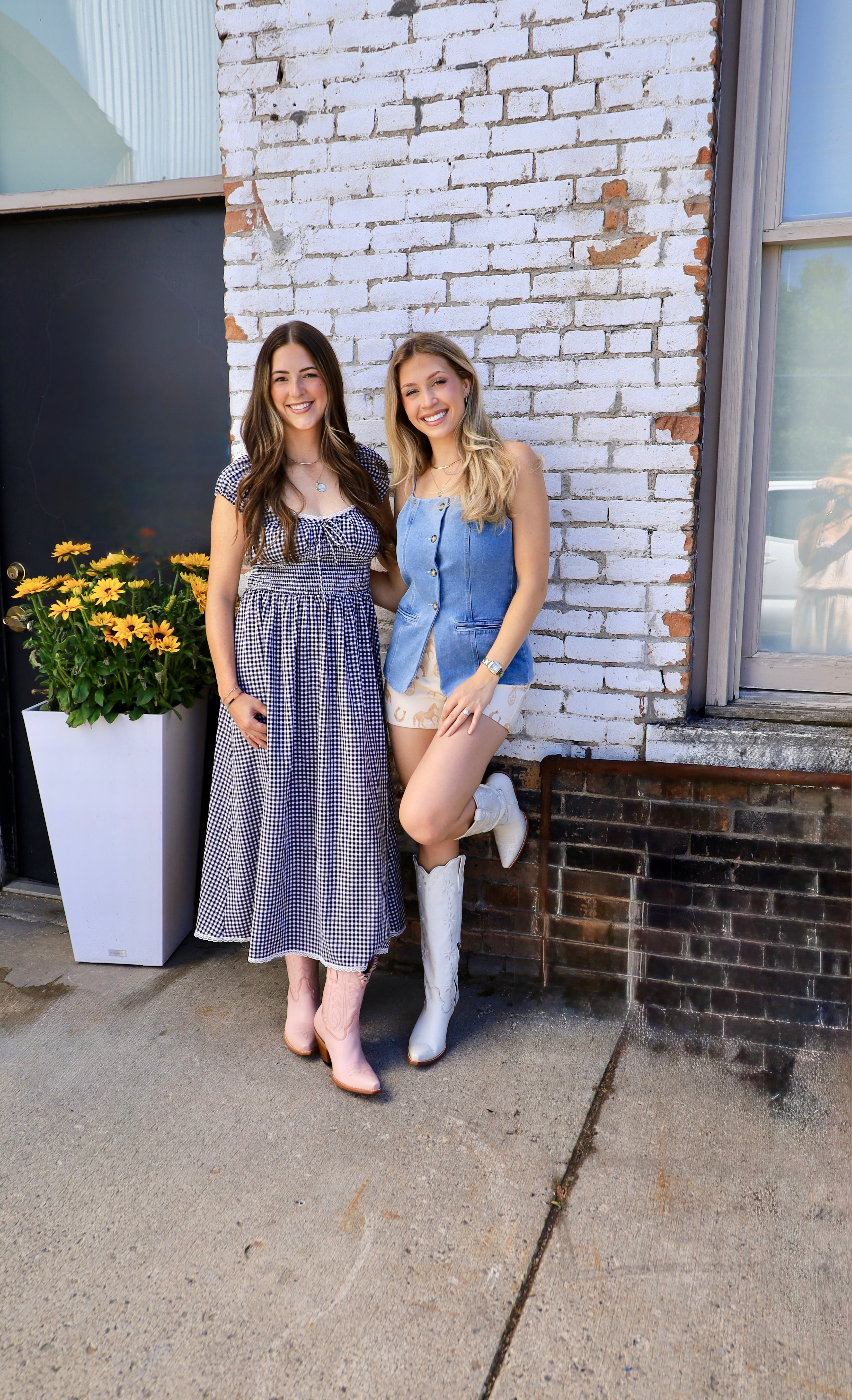 Light blue denim button-front vest styled with printed shorts and white cowboy boots on blonde model.