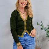 Dark olive green cardigan with contrast trim, gold buttons, styled with blue high-waist jeans and gold jewelry.