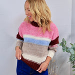 Chunky knit striped crewneck sweater in pink, burgundy, blue, and gray, styled with blue jeans.