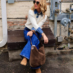 Woman wearing cream Oxford detailed sweater over denim shirt with flare jeans and ankle boots
