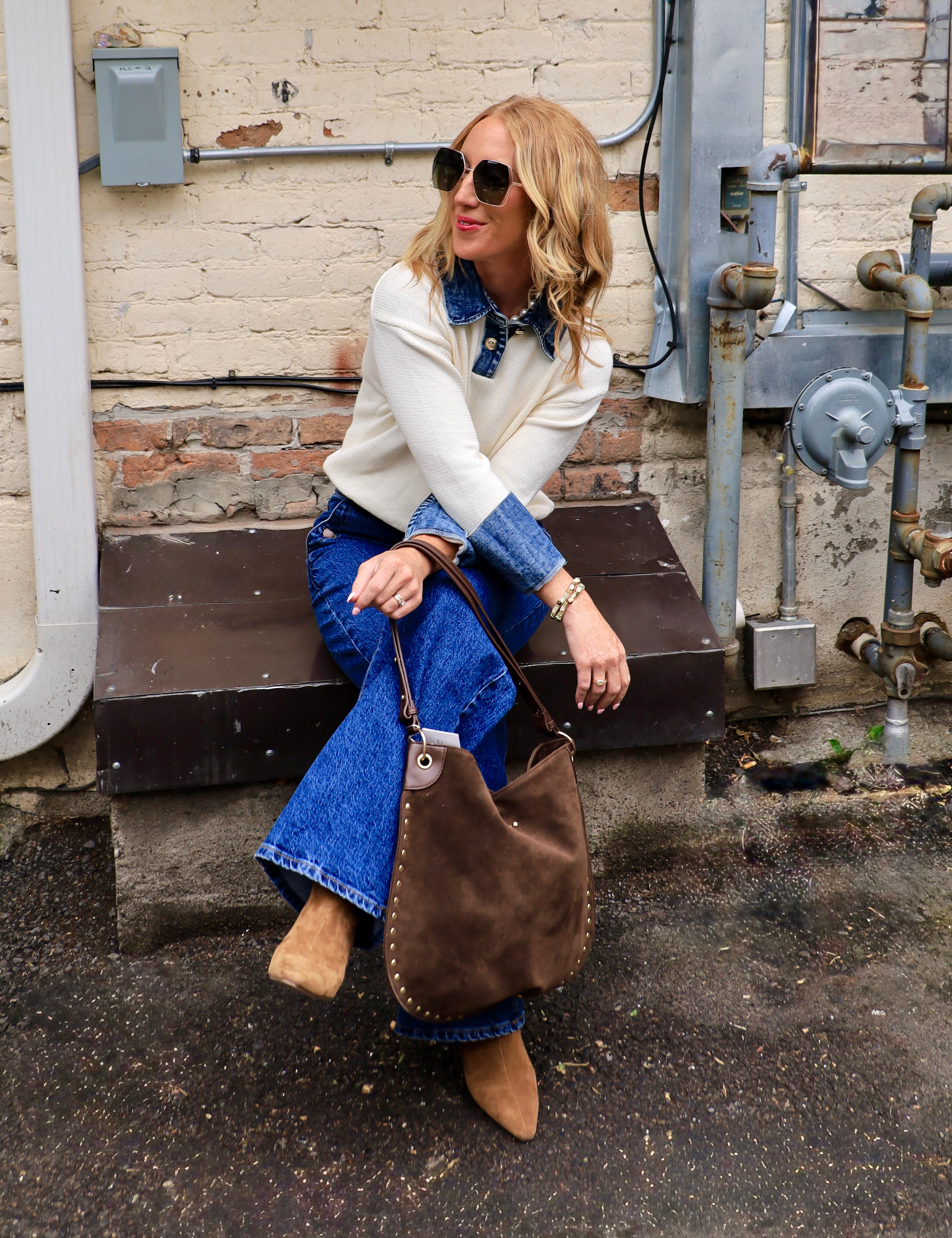 Woman wearing cream Oxford detailed sweater over denim shirt with flare jeans and ankle boots