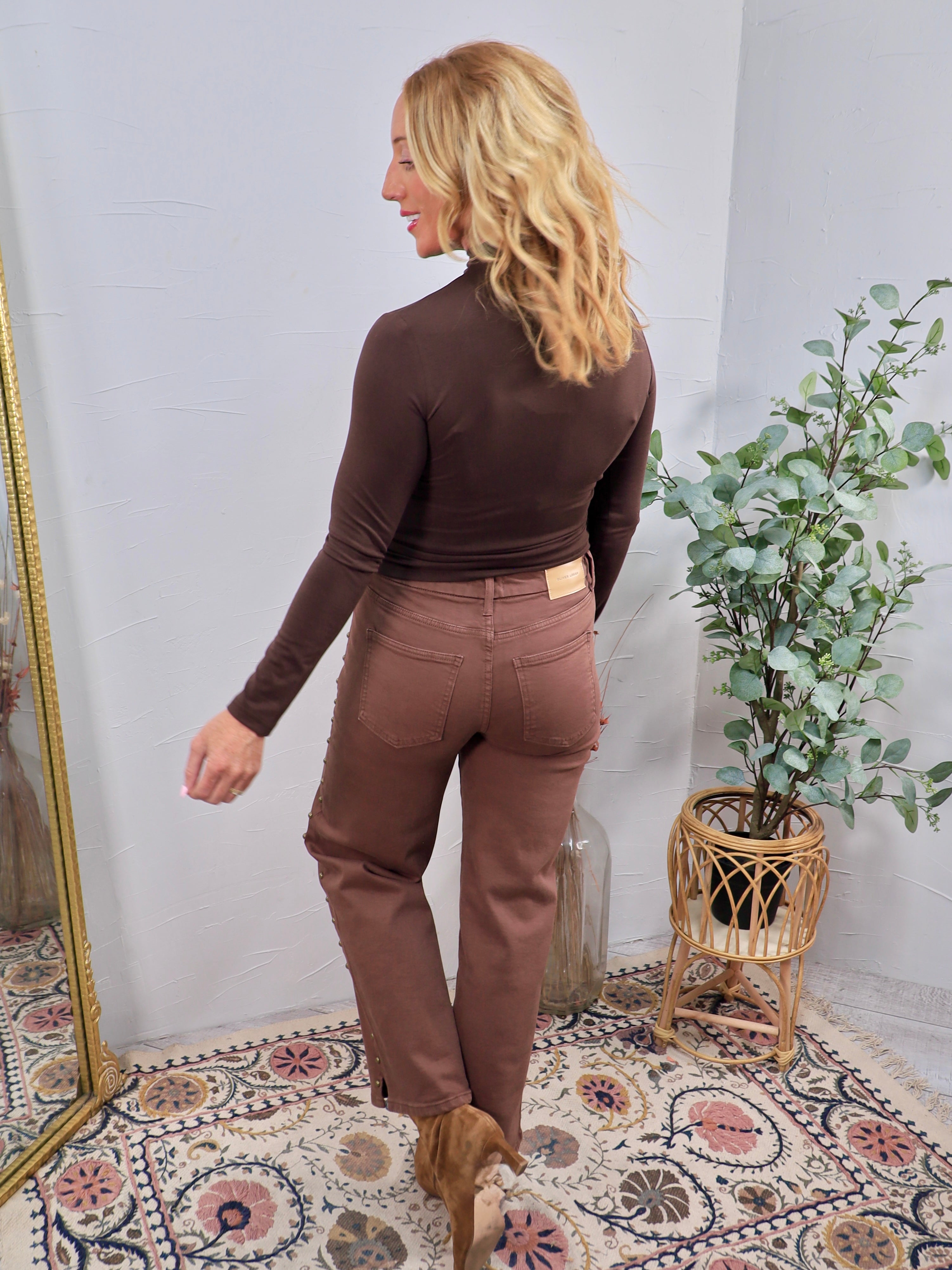 Brown studded straight-leg denim jeans styled with dark brown turtleneck bodysuit and tan cowboy boots, back view.