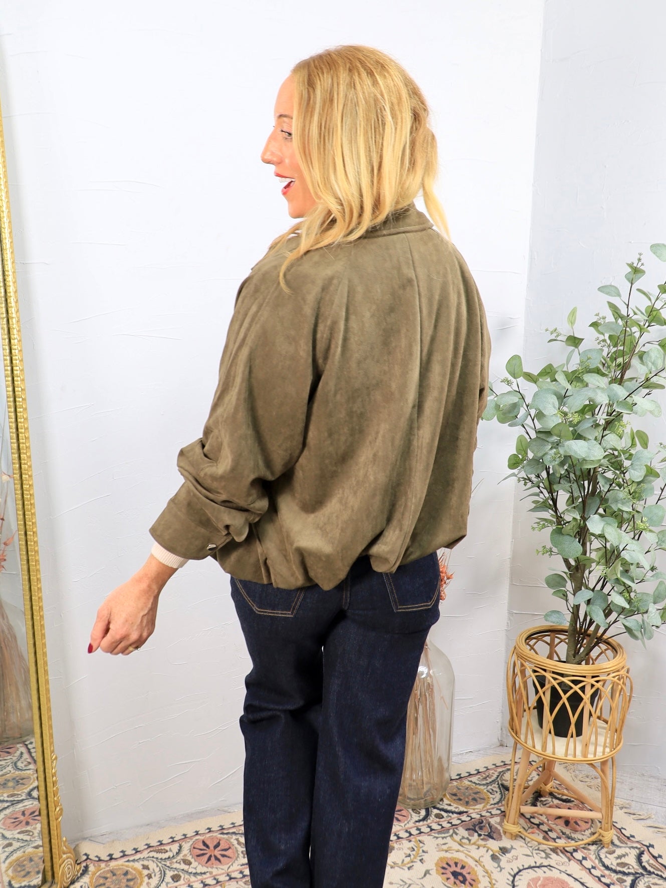 Olive green ruched suede jacket with rolled sleeves, styled with dark navy wide-leg jeans, back view.