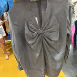 Gray houndstooth patterned blouse with large bow detail at front, long sleeves, being held up in store setting.