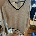Beige v-neck sweater with black contrast trim detail on hanger in boutique