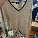 Beige v-neck sweater with black contrast trim detail on hanger in boutique