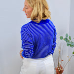 Blue and white striped long-sleeve turtleneck top styled with white wide-leg jeans, rear view.