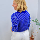 Blue and white striped long-sleeve turtleneck top styled with white wide-leg jeans, rear view.