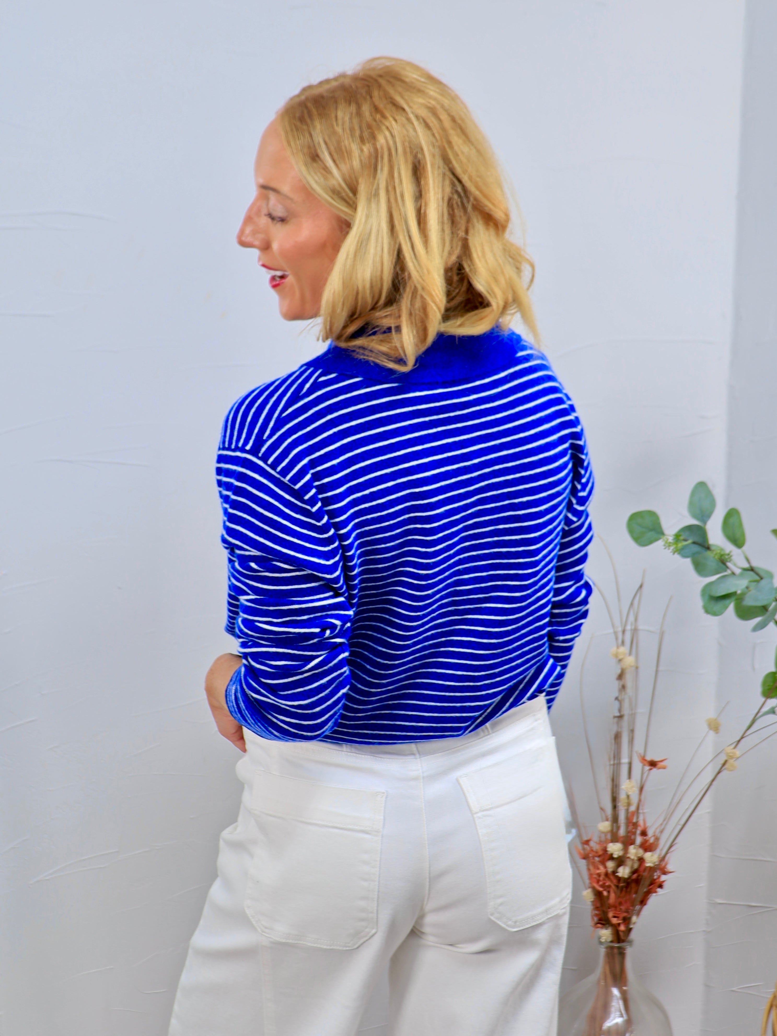 Blue and white striped long-sleeve turtleneck top styled with white wide-leg jeans, rear view.