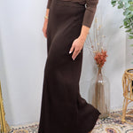 Woman wearing a chocolate brown ribbed pleated maxi skirt with a fitted long-sleeve top and tan flats