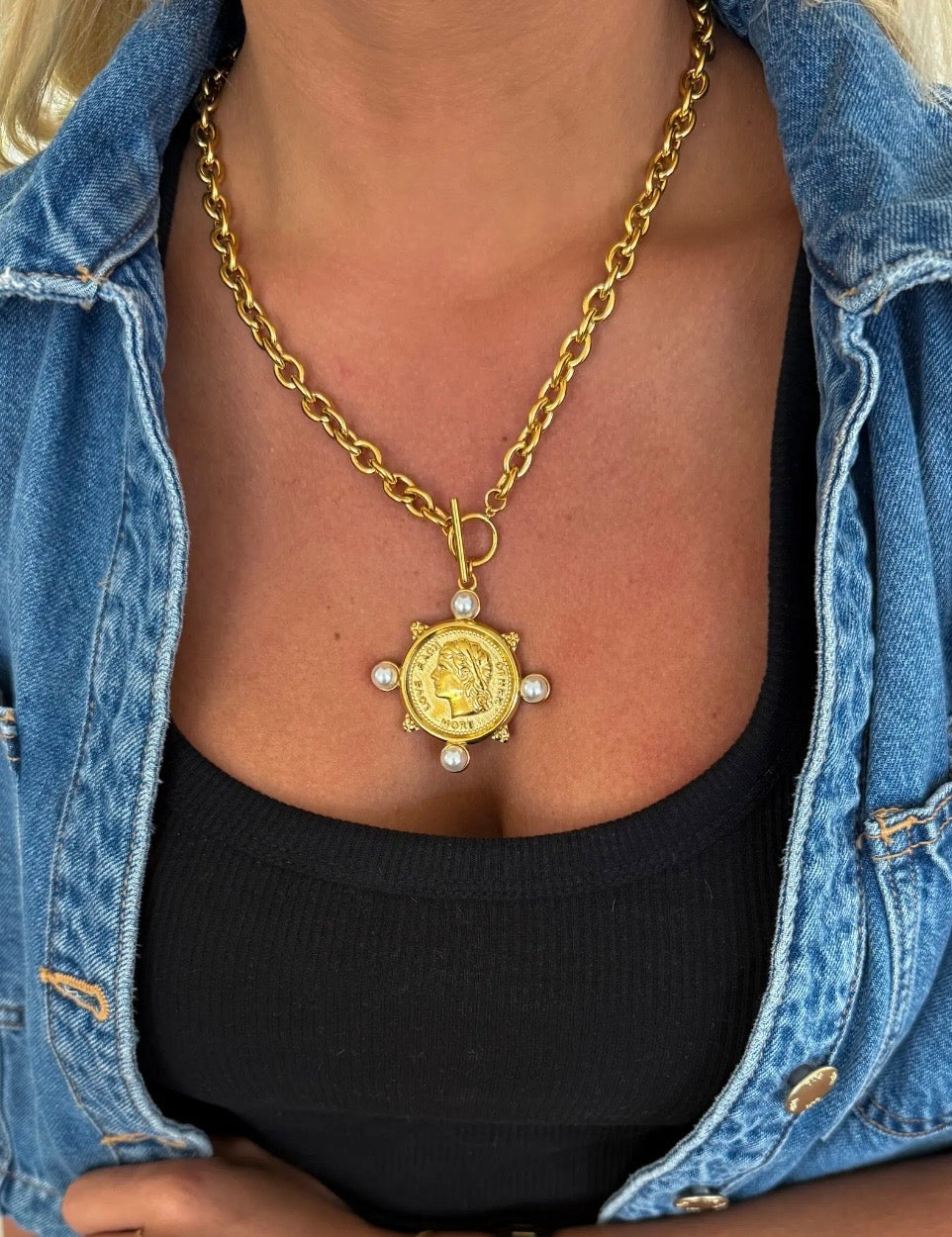 Gold chunky chain necklace with antique coin pendant and four pearl accents worn over black top