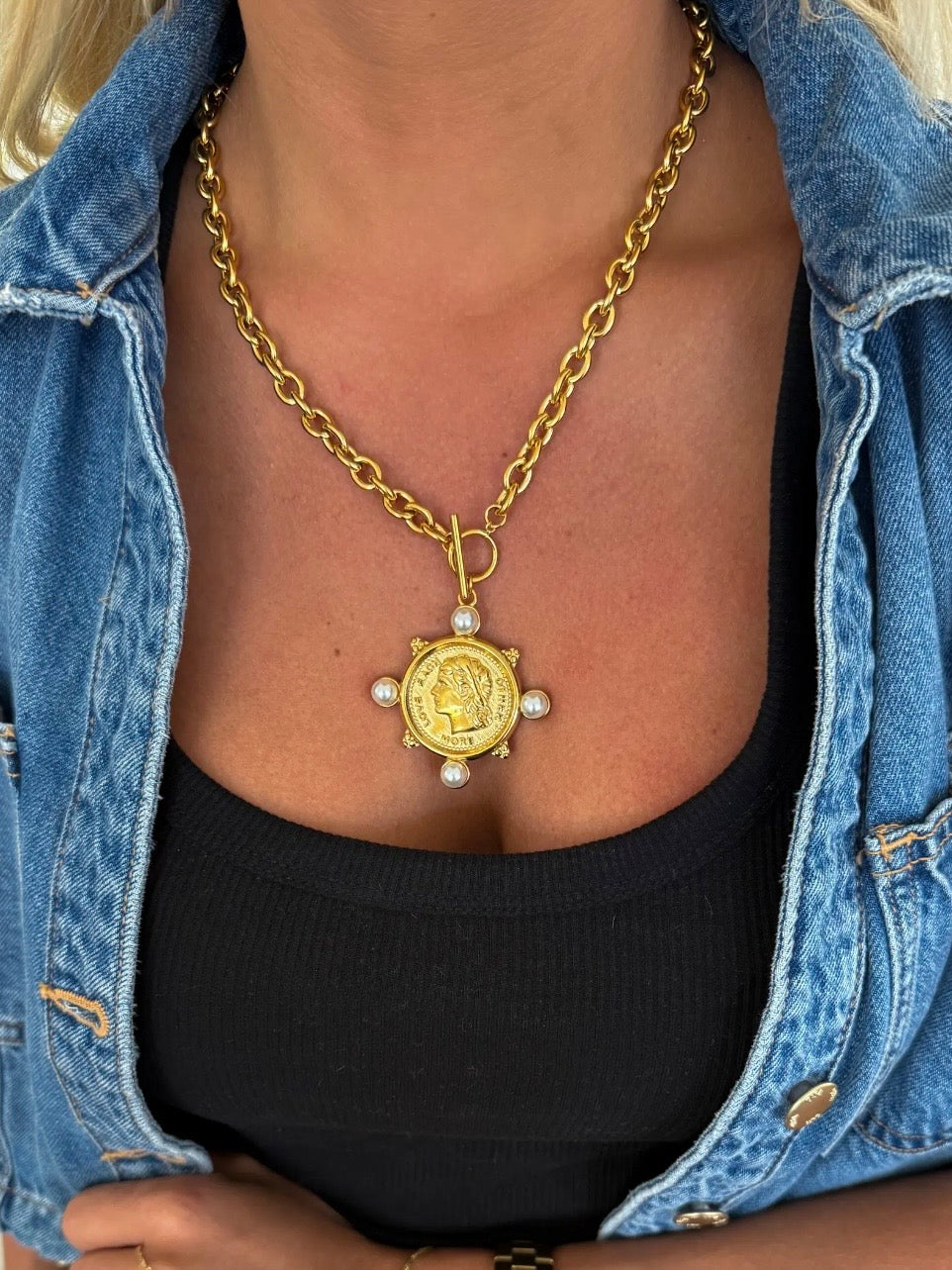 Gold chunky chain necklace with antique coin pendant and four pearl accents worn over black top