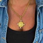 Gold chunky chain necklace with antique coin pendant and four pearl accents worn over black top
