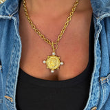Gold chunky chain necklace with antique coin pendant and four pearl accents worn over black top