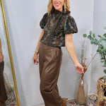 Dark floral print puff sleeve blouse with neck tie detail, styled with brown faux leather trousers.