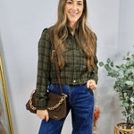 Woman wearing olive green plaid cropped button-up shirt with wide-leg blue jeans and brown crossbody bag
