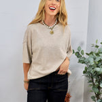 Beige oversized knit short-sleeve sweater tee styled with dark jeans and layered pearl gold coin necklace.