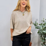 Beige oversized knit short-sleeve sweater tee styled with dark jeans and layered pearl gold coin necklace.