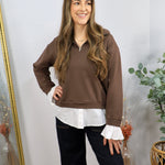 Brown half-zip pullover layered over white button-down shirt, styled with dark wide-leg jeans.