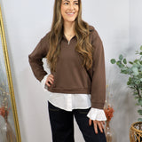 Brown half-zip pullover layered over white button-down shirt, styled with dark wide-leg jeans.