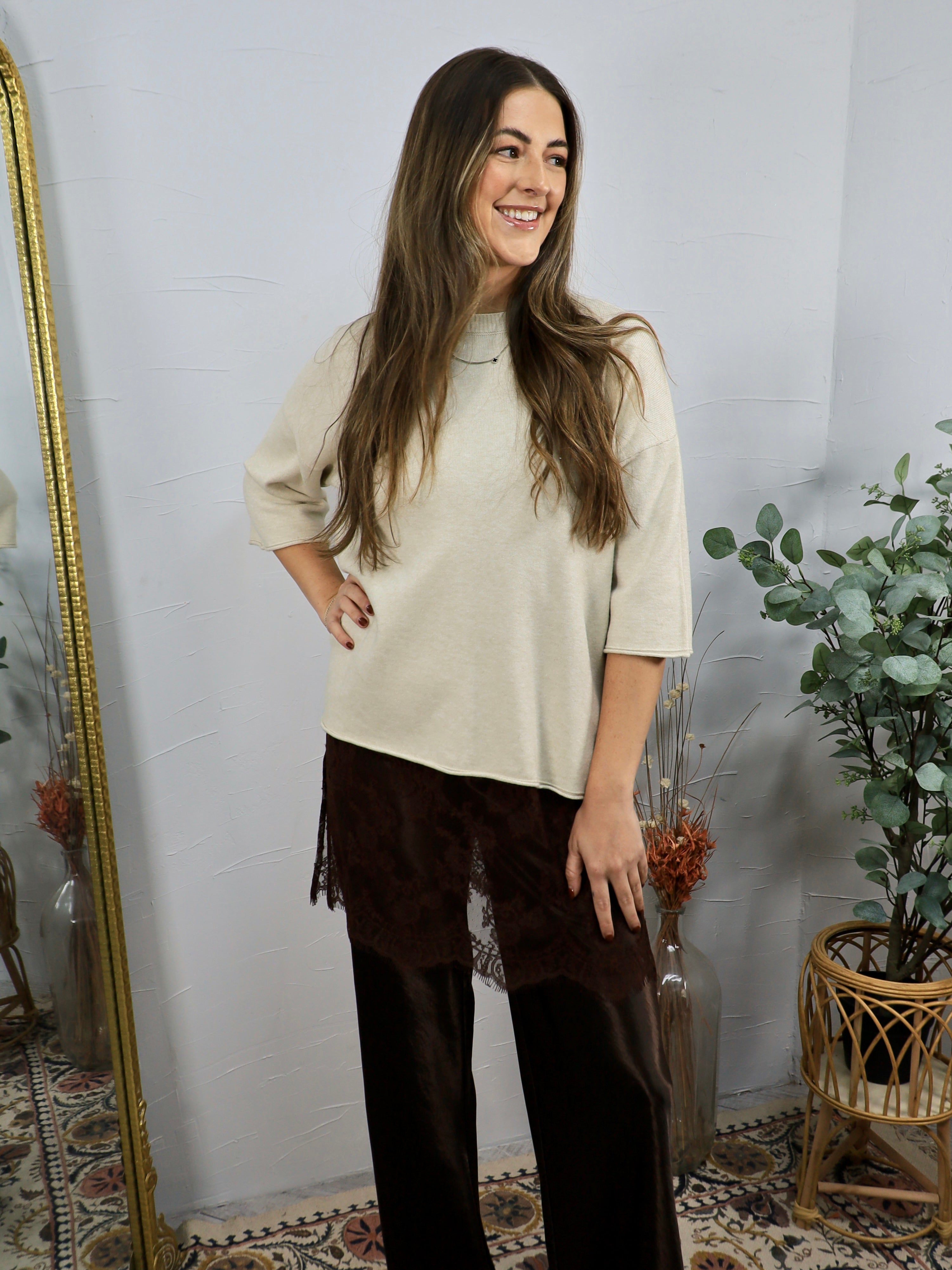 Cream short-sleeve knit top with mock neck, worn with dark brown wide-leg lace-trim pants.