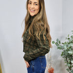 Green and brown plaid cropped button-up shirt styled with blue high-waisted jeans, side profile view.