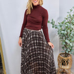 Brown and cream plaid pleated maxi skirt styled with burgundy turtleneck, floor-length, flowing silhouette.