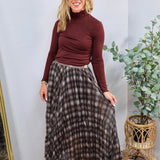 Brown and cream plaid pleated maxi skirt styled with burgundy turtleneck, floor-length, flowing silhouette.