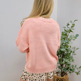 Pink oversized knit sweater styled over a spotted mini skirt, shown from the back view.