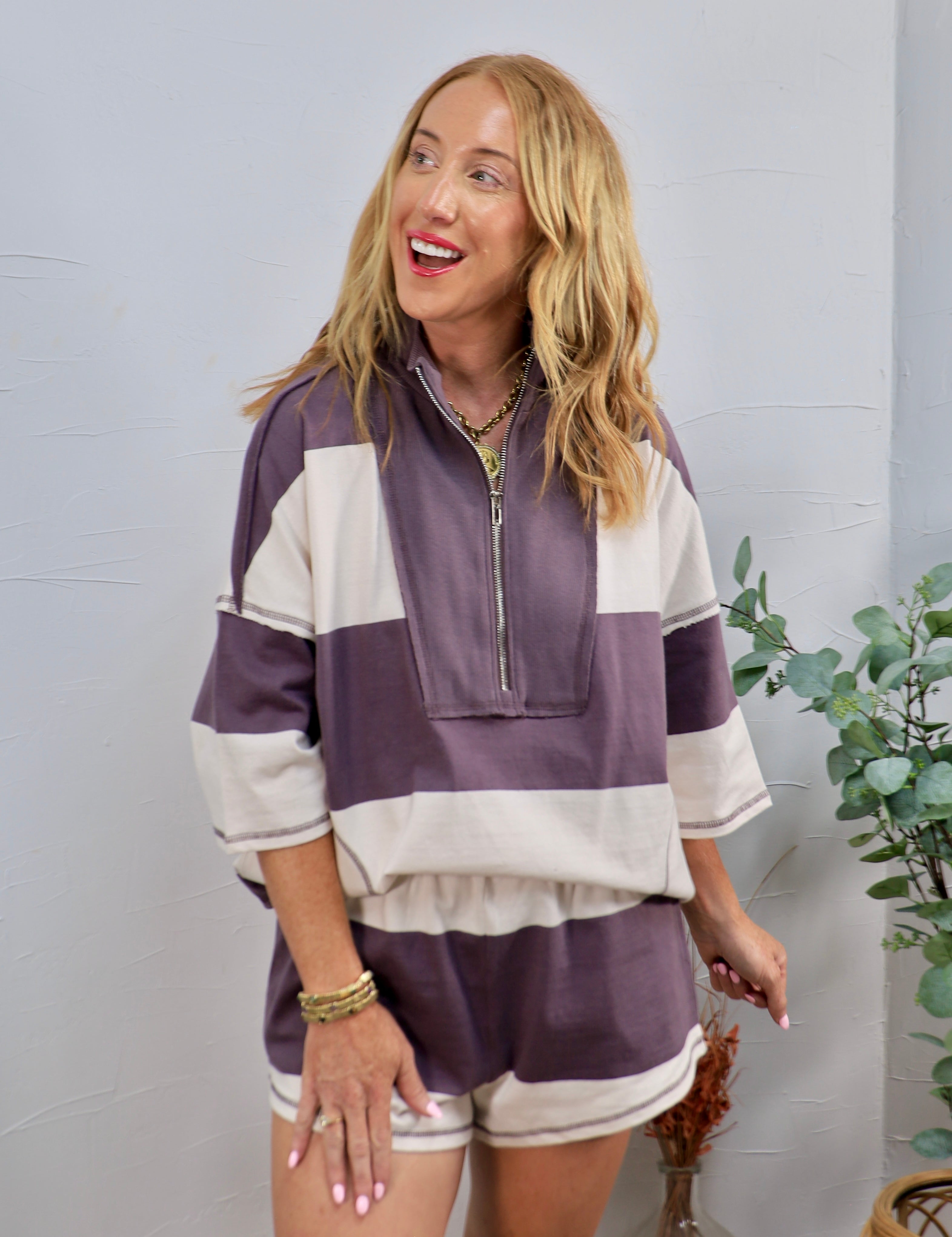 Woman wearing a purple and cream striped half-zip oversized lounge top with matching shorts