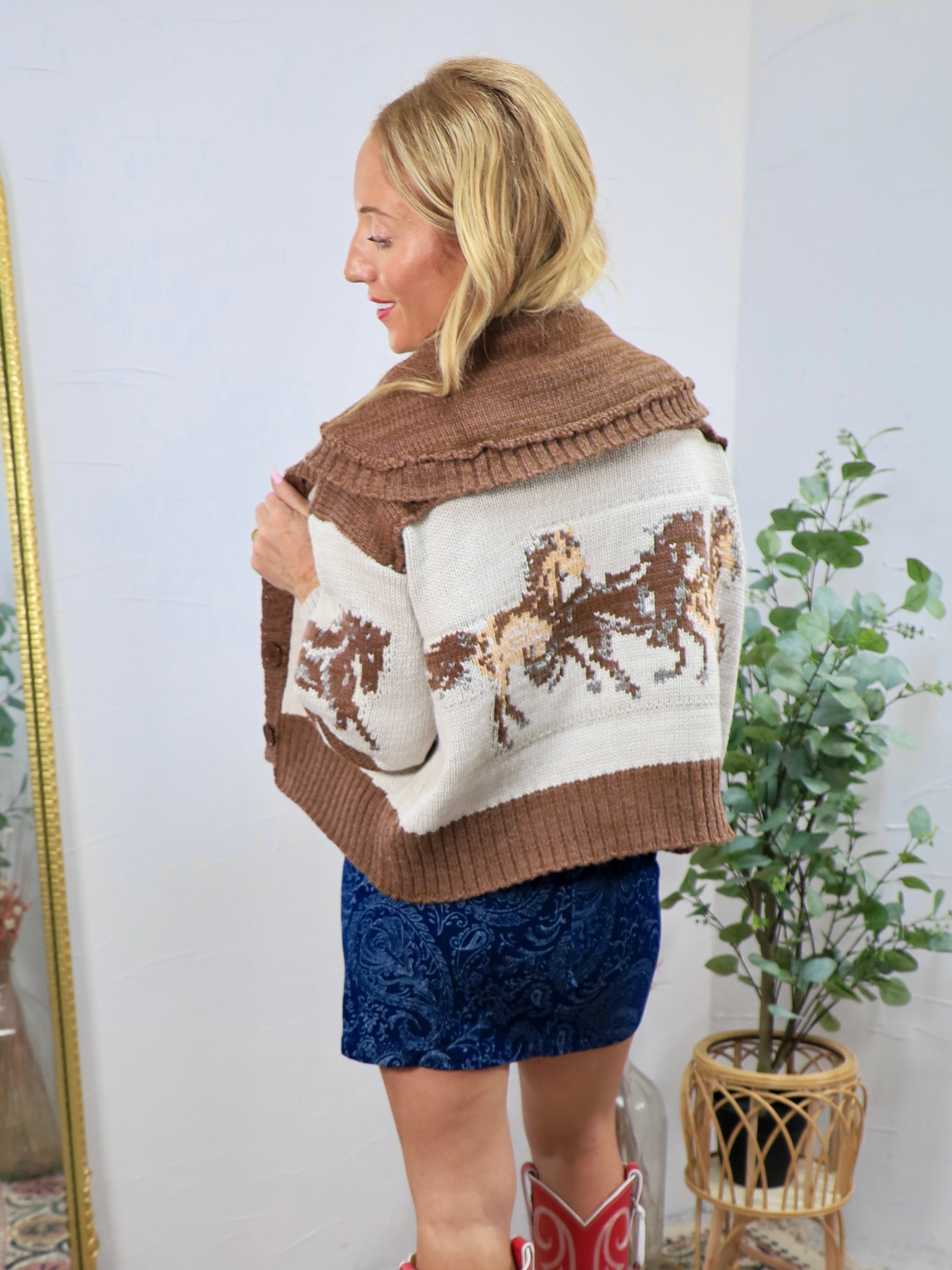 Brown and cream knit horse-print sweater with wide collar, styled with blue paisley mini skirt and red cowboy boots.