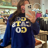Navy blue "Go Cats Go" graphic sweatshirt with patchwork appliqué lettering in gold and gingham patterns.