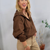 Chocolate brown hooded bomber jacket with zip front, styled with khaki trousers and gold jewelry.