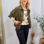 Olive green ruched suede zip-up jacket styled open over a floral sweater and dark flare jeans.