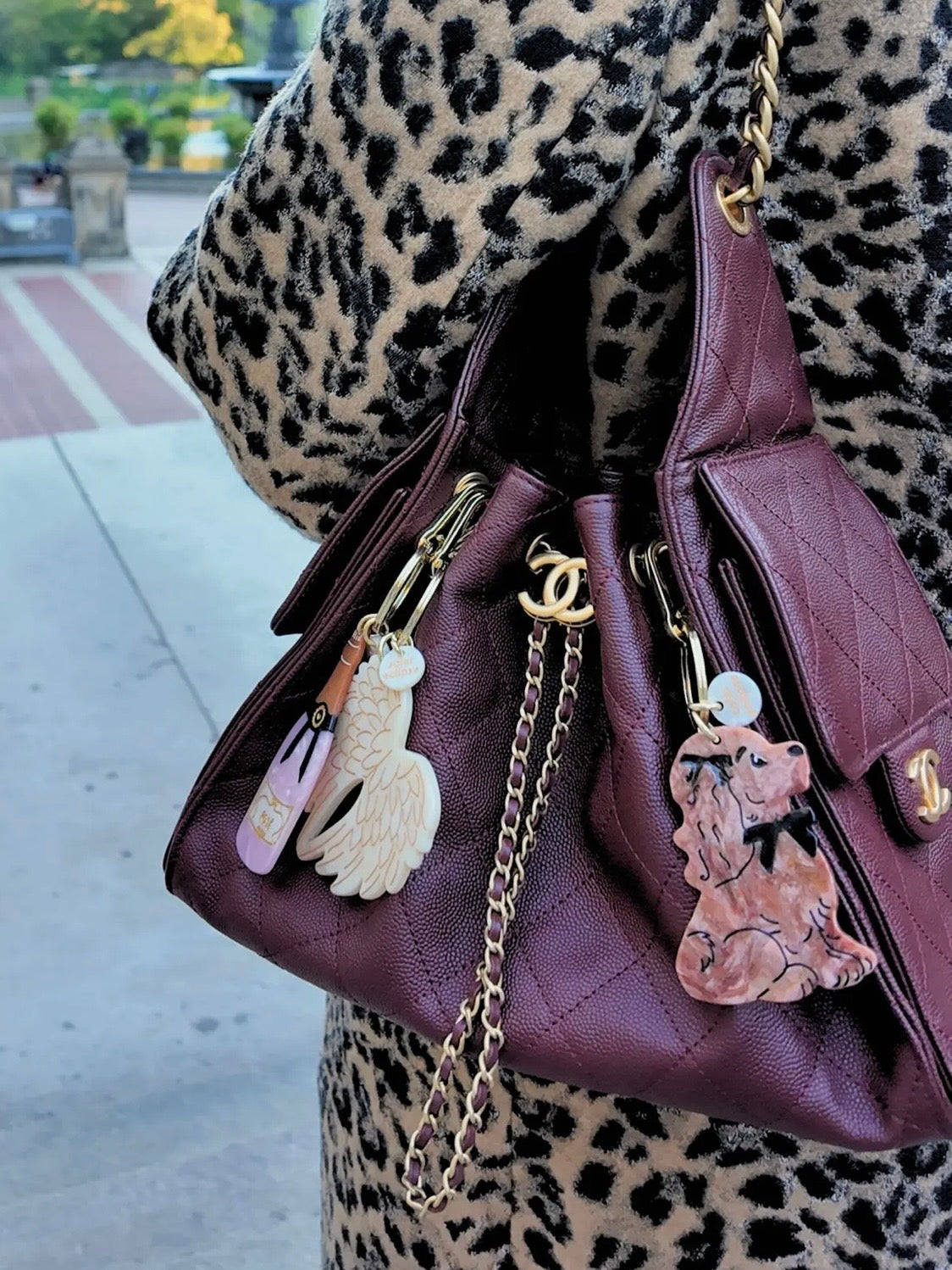 Burgundy quilted Chanel handbag with novelty keychains including a swan, nail polish, and dog charm.