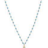 Gold-tone necklace with sky blue cylindrical beads and small turquoise teardrop pendant on white background
