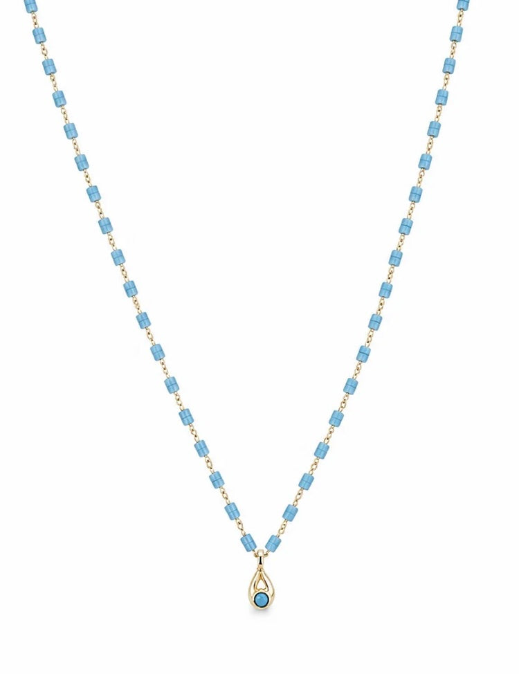 Gold-tone necklace with sky blue cylindrical beads and small turquoise teardrop pendant on white background