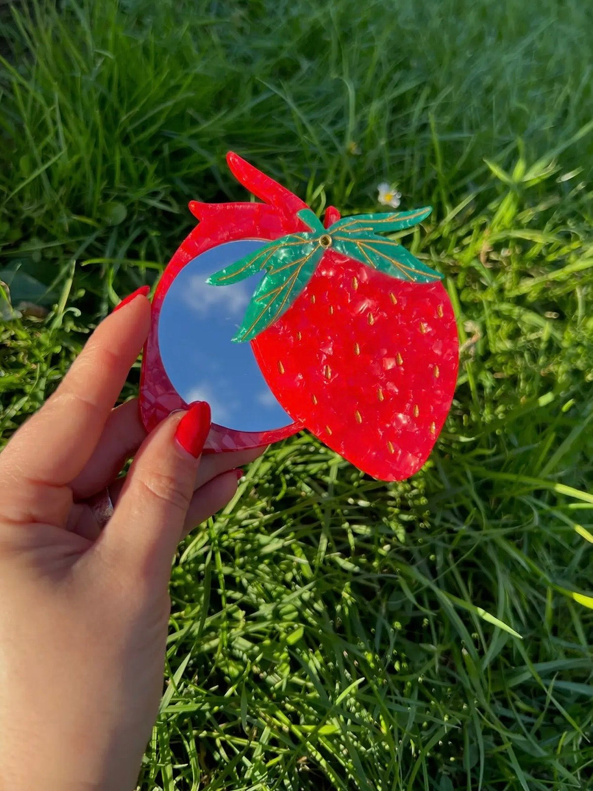 Strawberry-shaped compact mirror in red acrylic with green leaf detail and circular blue mirror insert.