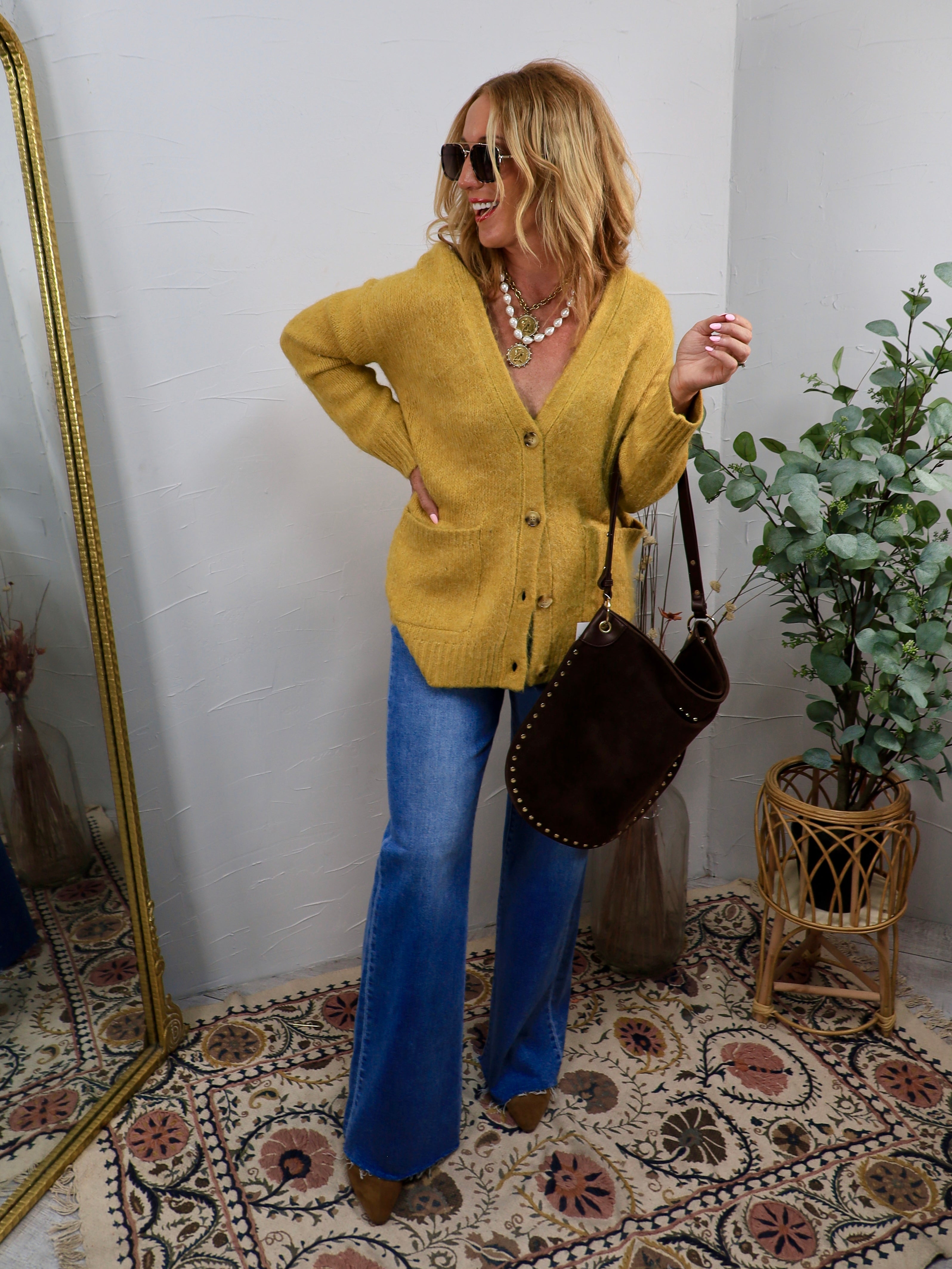 Woman wearing a chartreuse mustard oversized button-front cardigan with wide-leg jeans and brown boots