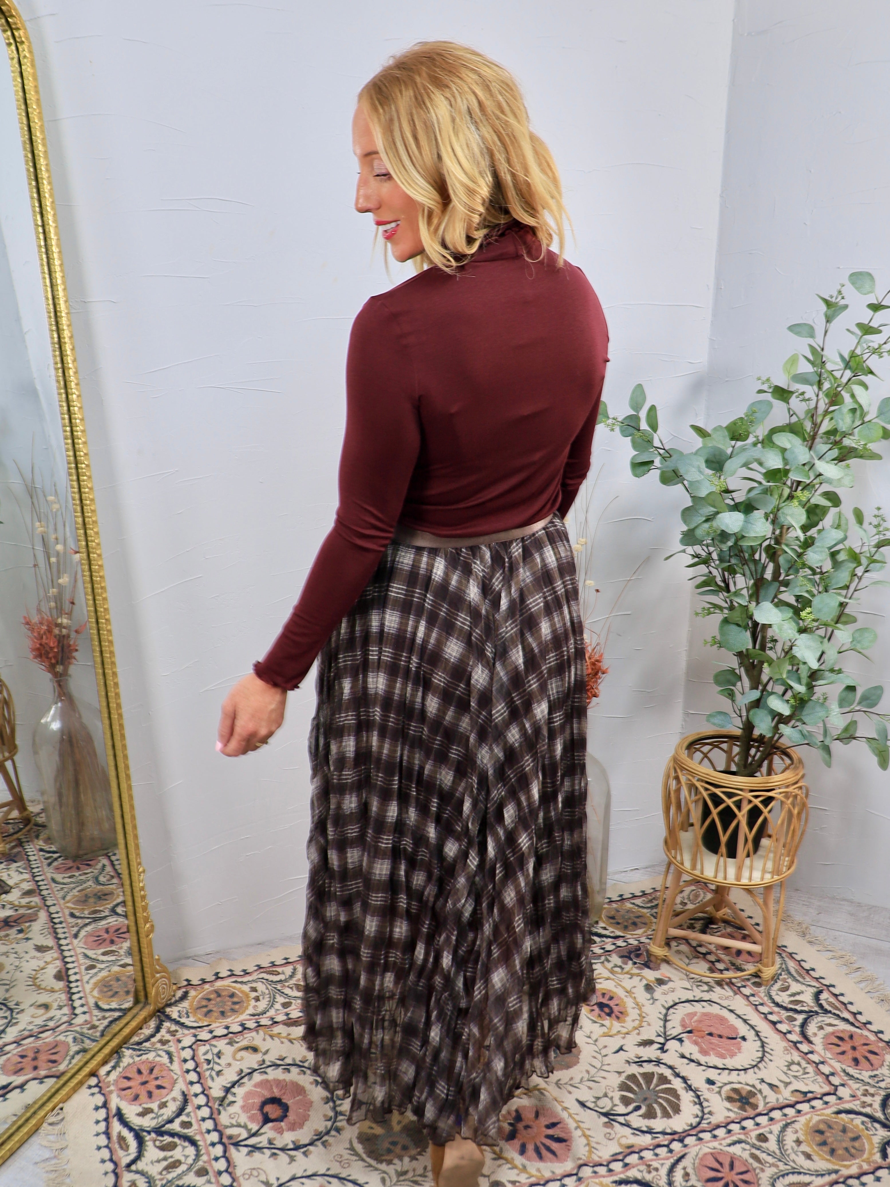 Brown and cream plaid maxi skirt styled with burgundy turtleneck top, flowing tiered silhouette, elastic waistband.