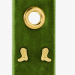 Pair of gold cowboy boot stud earrings displayed on a green velvet jewelry card with gold grommet