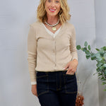 Beige ribbed cardigan layered over cream top, styled with dark wash jeans and pearl gold pendant necklace.